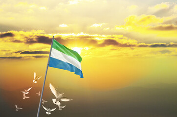 Sierra Leone flag waving with flying doves against sunset or sunrise. Sierra Leone flag for...
