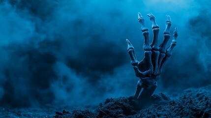 Fototapeta premium Eerie Skeleton Hand Emerging from Ground in Halloween Scene with Blue Tones and Foggy Atmosphere