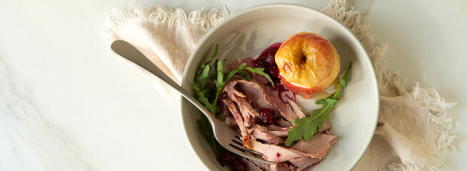 bowl of duck breast with baked apple on light table