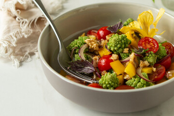 bowl of salad with romanesco cauliflower and cherry tomatoes on light table