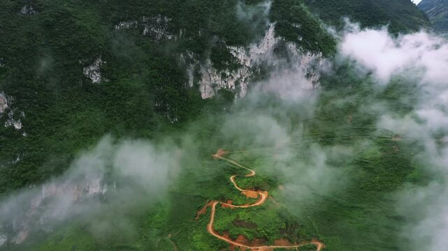 Drone of green mountains, nature and highway for travel, adventure and holiday with eco tourism background. Aerial view of a green landscape, clouds or road infrastructure in Vietnam, Ma Pi Leng Pass