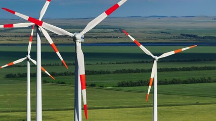 Footage of wind turbines rising above agricultural fields shows the harmonious combination of renewable energy and rural landscapes. The movement of the blades, open spaces.