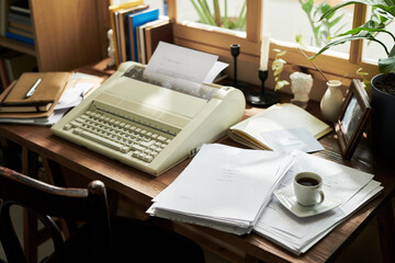 Sunlit office scene showcasing vintage typewriter surrounded by documents, books, and coffee cup, offering nostalgic and productive atmosphere