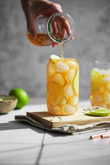 Glass of iced jasmine tea with fresh lime slices. Summer refreshing drink or cocktail. Homemade fruit green tea with ice. Bar, cafe menu. Tea is pouring into a glass.