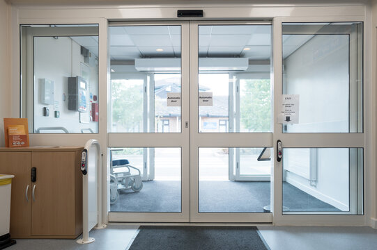 Automatic doors seen at the exit of an NHS outpatients department in a busy British hospital. The building  seen through the doors is an A and E department.