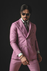 Fototapeta premium confident fashion guy with sunglasses wearing double breasted pink suit