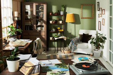 Cozy workspace featuring open books, plants, a comfortable chair, a vinyl record playing, and green decor creating a serene environment for work and relaxation