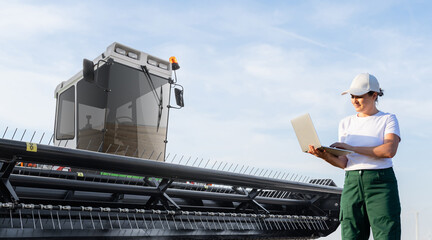 Female farmer with laptop on a background of harvester. Smart farming concept