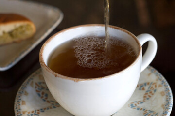 Herbal tea is poured into a mug on the table