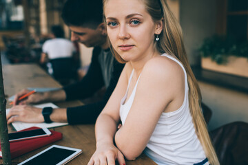 Pensive woman sitting at table with tablet next to male colleague