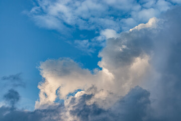 A stunning image of a vibrant blue sky with dramatic cumulus clouds. Sunlight softly illuminates the clouds, creating a tranquil, atmospheric scene, ideal for nature, weather, or serene backgrounds.