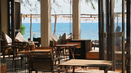 Cozy beachside restaurant with wooden furniture and scenic ocean view, perfect spot for dining and relaxation on sunny day, Outdoor Dining and Leisure