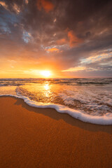 Scenic sunrise over sea splashing waves on the beach, exotic ocean shore sunset vertical view