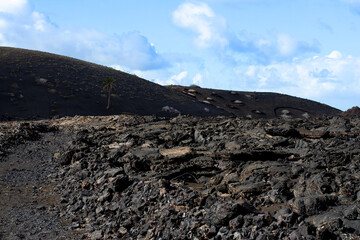 Road through the black lava field and volcanos on hiking Termesana route (Ruta de Termesana) in Timanfaya national park, Lanzarote, Canary Islands , Spain