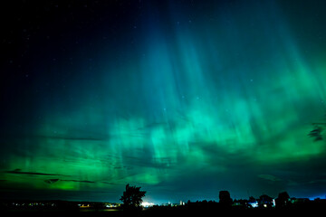 Fototapeta premium Northern lights dancing over the sky sky in the country road