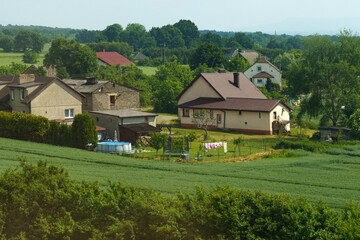 Serene countryside landscape showcasing quaint houses and vibrant green fields under a clear sky during the peaceful afternoon