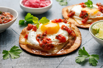 Huevos Rancheros tostadas with fried egg, tomato salsa, bean paste and cheese. Mexican food