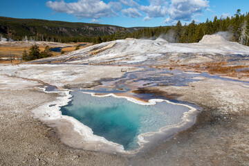 Geothermal Pool in Yellowstone National Park with Vibrant Blue Water and Surrounding Landscape