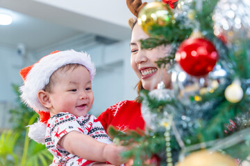 Baby in red hat on Christmas Day, filled with camera, presents and Christmas tree.