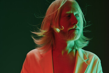 Portrait of a man with long hair against a colorful background, showcasing a striking blend of green and red lighting, evoking a modern, artistic vibe Ideal for creative projects