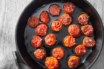 Spanish chorizo frying in olive oil in a cast iron frying pan. Edited with selective colour