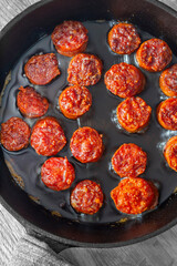 Spanish chorizo frying in olive oil in a cast iron frying pan. Edited with selective colour