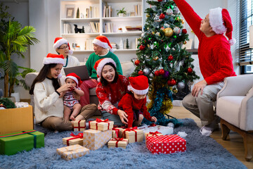 Asian family on Christmas Day. Everyone is happy together in a Christmas themed room filled with presents and orange lights.