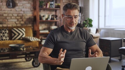 Focused coach or advisor participating in video conference, gesturing while sharing idea and...