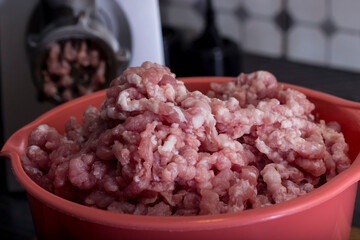 making minced meat using a meat grinder. minced meat in a colored bowl. the finished minced meat is taken in close-up directly from the meat grinder