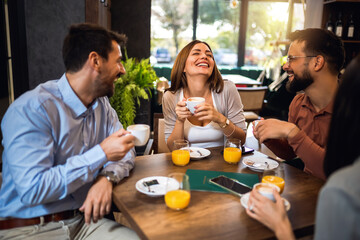 Group of friends chilling at the cafe. Talking, laughing and drinking coffee and orange juice.
