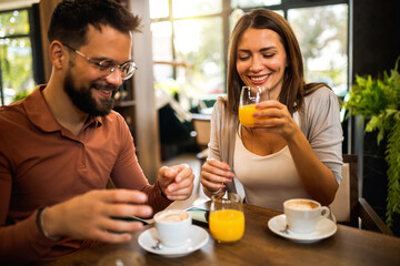 Two friends met at the cafe. Hanging out and drinking orange juice and coffee together.