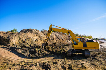 Obraz premium Backhoe working by digging soil at construction site