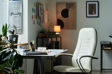 Contemporary home office featuring white ergonomic chair, desk with various office supplies,...