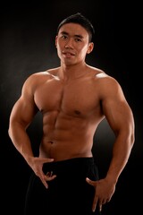 Fototapeta premium Musculat asian man bodybuilder posing against black background.