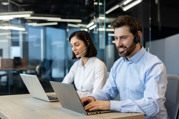 Customer service representatives engaged in professional work using headsets and laptops. Team collaboration and effective communication emphasized in a modern office environment