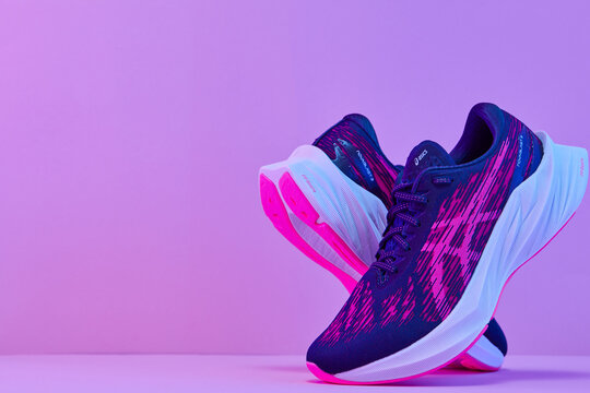 Zhlobin, Belarus - august 10, 2024: ASICS Novablast 3 Running Shoes on neon color background. ASICS is a Japanese athletic sneakers company which produces cushioning footwear.