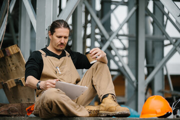 A worker on a construction site rests during a coffee break.