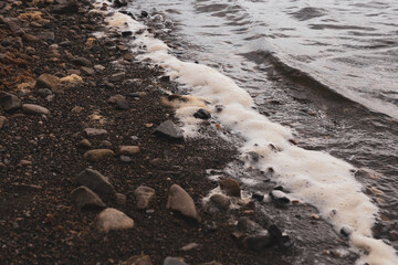 dirty foam on river is the result of river pollution by sewage