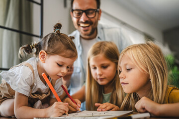 three young daughters draw and color in the notebook at home