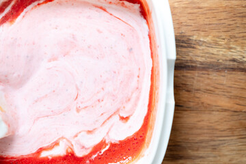 red and liquid strawberry jelly in a container and a yellow spatula for stirring after the blender