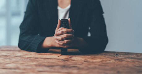 Awaiting Decision: Close-up of a woman's hands clasped together, conveying anticipation and uncertainty in a professional setting.  A minimalist aesthetic with a focus on detail emphasizes the weight 