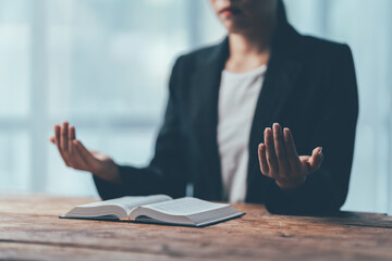 Finding Peace: A businesswoman finds solace and clarity through prayer at her desk, her open hands...