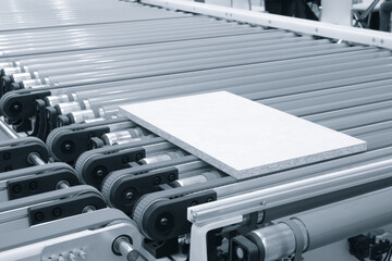 A conveyor belt with a white wooden board chipboard on it