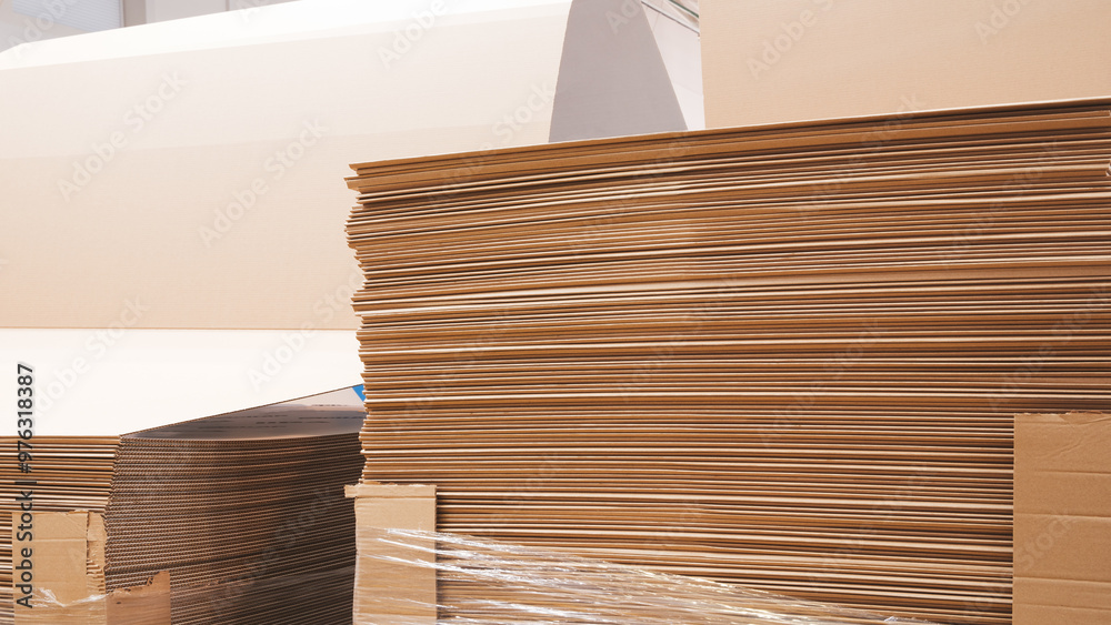 Poster A stack of cardboard boxes with a plastic wrap on top. The boxes are piled up and appear to be in a warehouse