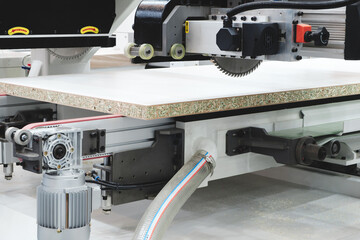 A woodworking shop with a large machine cutting a piece of wood. The machine is surrounded by a lot of dust and debris