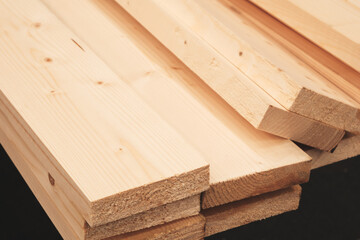 A pile of wood with a black background. The wood is stacked in a way that it looks like it's about to fall