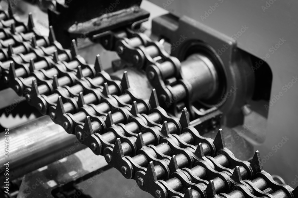 Poster A chain of metal links with many spikes. The chain is black and white. The chain is being made in a factory