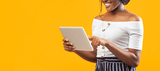 Unrecognizable Afro Girl Using Tablet Computer Standing Over Orange Studio Background. Cropped, Panorama, Free Space