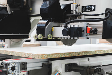 A woodworking shop with a large machine cutting a piece of wood. The machine is surrounded by a lot of dust and debris