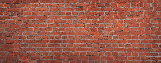 A brick wall with a red color. The wall is made of bricks and has a rough texture